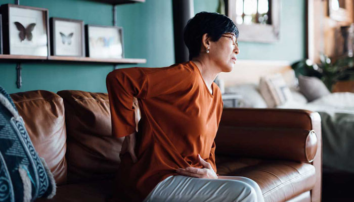 Woman holding her back in pain