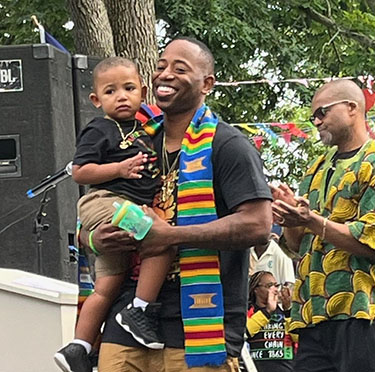 Anthony Gray carrying a small boy while accepting his award