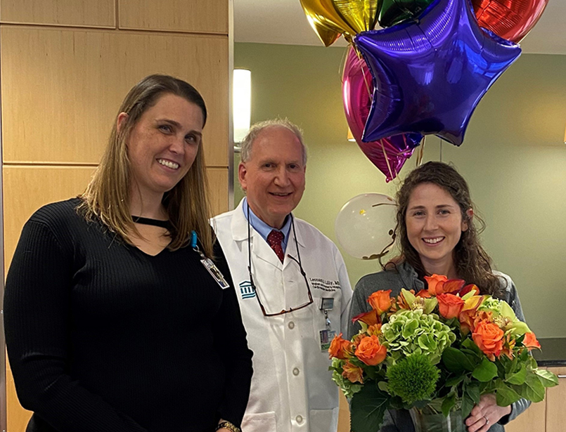 Woman holding flowers and balloons next to two colleagues