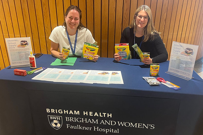 Two women sitting at a table collecting school supplies