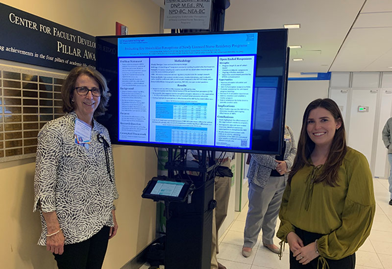 Helene Bowen Brady and Christine Sgroi standing with poster