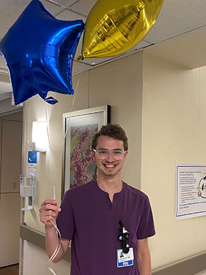 James Brawn holding balloons in the hospital hallway