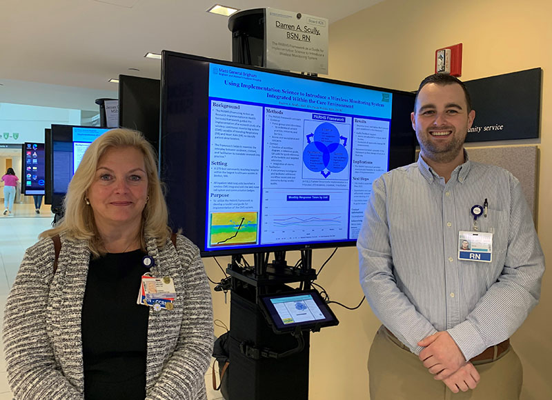 Paula Wolski and Darren A. Scully standing with poster