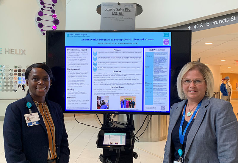 Suzelle Saint-Eloi and Jennifer Capone standing with poster